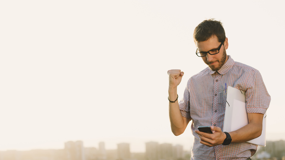 Man looking at mobile doing fist pump in air