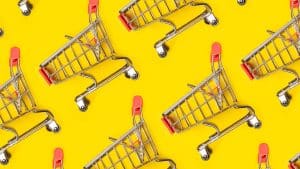 Multiple mini shopping trollies against a bright yellow background