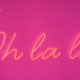A yellow neon light sign reading 'Oh la la' on a pink background