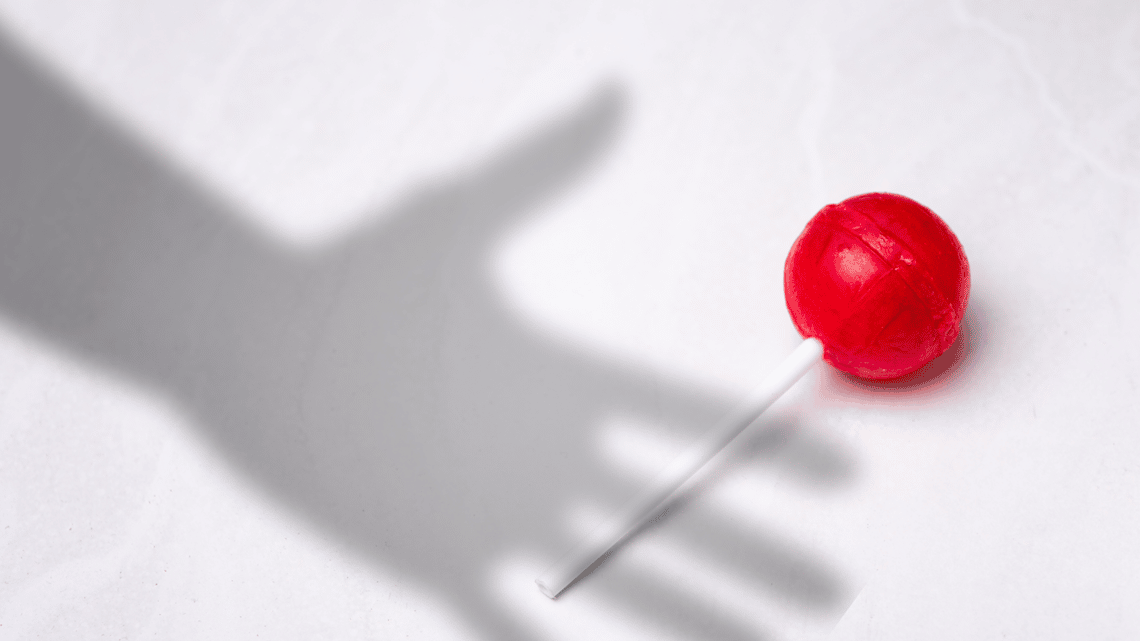 shadow of a child's hand reaching for a lollypop