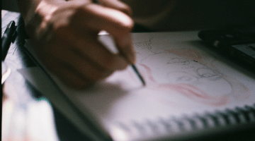 image of note pad as someone draws a face
