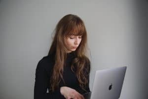 A young person looking at their laptop with a neutral look on their face