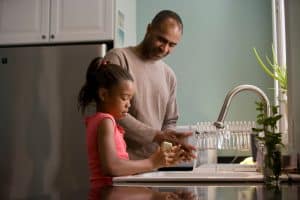 Father and daughter talking at a sink