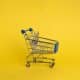 Picture of a small supermarket trolley on a yellow background