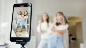 Two girls recording themselves using a phone stand