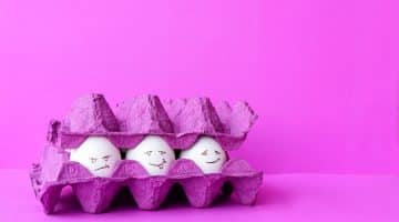 A purple egg carton with three eggs inside showing happy, angry and neutral expressions.
