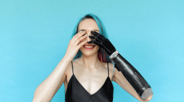 A female who has a prosthetic arm raising her hand to her head